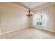 Dining room with neutral tile flooring, chandelier, large window with white drapes, and wainscotting at 1024 Featherstone Cir, Ocoee, FL 34761