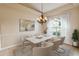 Dining room with neutral tile flooring, chandelier, white drapes, wainscotting, and virtual staging at 1024 Featherstone Cir, Ocoee, FL 34761