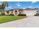 Charming single-story home with manicured lawn, arched entryway, two-car garage, and mature palm trees at 1024 Featherstone Cir, Ocoee, FL 34761