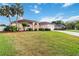 Well-maintained home with large front yard and lush landscaping under a blue sky with scattered clouds at 1024 Featherstone Cir, Ocoee, FL 34761