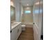 Bright bathroom featuring a shower over tub, white vanity, and wood-look tile flooring at 1043 Gloryland Ct, Sanford, FL 32771