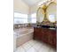 Primary bathroom featuring tiled floors, a double sink vanity, decorative mirrors, and soaking tub at 12543 Waterhaven Cir, Orlando, FL 32828