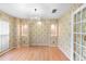 Dining room featuring hardwood floors, statement wallpaper, elegant chandelier, and french doors at 12543 Waterhaven Cir, Orlando, FL 32828