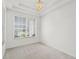 Bright, carpeted bedroom with large window, white walls, ceiling trim, and gold chandelier at 212 Tavestock Loop, Winter Springs, FL 32708