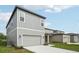 Exterior view of a two-story home with a gray garage door and driveway at 2467 Zuni Road, St Cloud, FL 34771