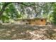 View of the back of a tan house, showcasing the backyard with tree coverage and a patio at 2918 Croton Rd, Apopka, FL 32703