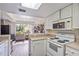 Cozy kitchen featuring white appliances, skylight, and an open view into the adjacent living area at 318 Australian Way, Davenport, FL 33897