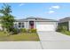 Charming single Gathering home featuring a 2-car garage, landscaped yard, and red front door at 3341 Lounging Wren Ln, Bartow, FL 33830