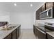 Modern kitchen featuring granite countertops, stainless steel appliances, and dark wood cabinets at 3341 Lounging Wren Ln, Bartow, FL 33830