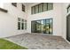 Spacious outdoor patio with stone pavers and modern stucco exterior with large windows and sliding glass doors at 4047 Isabella Cir, Windermere, FL 34786