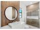 Modern bathroom featuring wood accent wall, round mirror, sleek vanity, and glass-enclosed shower at 4047 Isabella Cir, Windermere, FL 34786