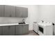 Functional laundry room with modern gray cabinets, quartz countertops, sink, washer and dryer at 4047 Isabella Cir, Windermere, FL 34786