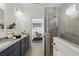 Well-lit bathroom featuring a double vanity and a tiled glass shower with a view to the bedroom at 4338 Davos Dr, Clermont, FL 34711