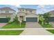 Attractive two-story home featuring stone detailing, a paved driveway, and a neatly landscaped lawn at 4338 Davos Dr, Clermont, FL 34711