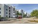 Modern condo building with ample parking, palm trees, and well-maintained landscaping under a bright sky at 4731 Clock Tower Dr # 104, Kissimmee, FL 34746