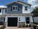 Two-story townhome featuring stone accents, a black garage door, and a mix of blue and white siding at 5103 Prairie Preserve Run, St Cloud, FL 34772