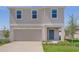 Charming two-story home featuring a tidy lawn, an attached two-car garage, and a welcoming blue front door at 5109 Forget Me Not Ave, Lake Hamilton, FL 33851