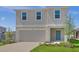 Two-story home featuring a two-car garage, neat landscaping, and a welcoming blue front door at 5109 Forget Me Not Ave, Lake Hamilton, FL 33851