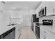 Modern kitchen with white cabinets, stainless steel appliances, modern lighting, and a door leading to another room at 5109 Forget Me Not Ave, Lake Hamilton, FL 33851