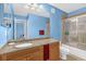 Bathroom featuring granite countertops, wood cabinets, and a shower/bathtub combo with glass doors at 5452 E Michigan St # 7, Orlando, FL 32812