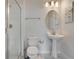 This bathroom includes a glass-enclosed shower, toilet, sink with pedestal, decorative mirror, and modern lighting at 9034 Stinger Dr, Davenport, FL 33896