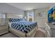 This bedroom boasts a bed with patterned bedding, a nightstand, contemporary artwork, and a flat-screen television at 9034 Stinger Dr, Davenport, FL 33896