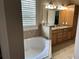 Bright bathroom showcasing a soaking tub, double sink vanity, and light wood cabinets at 11120 Se 168Th Loop, Summerfield, FL 34491
