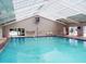 A bright indoor swimming pool with a high ceiling, ample natural light, and comfortable seating at 11120 Se 168Th Loop, Summerfield, FL 34491