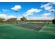 Well-maintained tennis courts with green surface, surrounded by fencing and blue skies at 13622 Cygnus Dr, Orlando, FL 32828