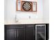 Entertain guests with this bar area featuring dark cabinetry, a sink, and a mini-fridge for drinks at 16054 Johns Lake Overlook Dr, Winter Garden, FL 34787