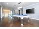 Game room boasts a modern pool table, sleek lighting, hardwood floors, and access to a glass-enclosed balcony at 16054 Johns Lake Overlook Dr, Winter Garden, FL 34787