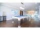 Bright game room features a modern pool table, hardwood floors, and beautiful glass-enclosed balcony overlooking a lake at 16054 Johns Lake Overlook Dr, Winter Garden, FL 34787