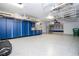 Organized garage featuring epoxy flooring and blue storage cabinets, maximizing space at 16054 Johns Lake Overlook Dr, Winter Garden, FL 34787