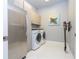 Functional laundry room with stainless steel refrigerator, washer, dryer, and ample cabinet space at 16054 Johns Lake Overlook Dr, Winter Garden, FL 34787