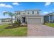 Inviting two-story home featuring a manicured lawn and a brick driveway at 1616 Eucalyptus Way, Davenport, FL 33837