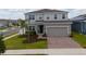 Two-story home features a brick driveway, a two-car garage, and a well-manicured lawn with small palm trees at 1616 Eucalyptus Way, Davenport, FL 33837