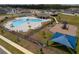 A bright community pool and playground area, surrounded by a fence and lush landscaping at 1616 Eucalyptus Way, Davenport, FL 33837