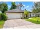 Charming home featuring a two-car garage, lush landscaping, and a paver driveway at 169 Winding Oaks Ln, Oviedo, FL 32765
