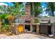 Outdoor kitchen with brick pizza oven and gas grill offers a luxurious space for outdoor cooking and dining at 169 Winding Oaks Ln, Oviedo, FL 32765