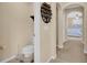 View of a toilet and decorative shelf leading to a bedroom with a ceiling fan and window at 23520 San Sebastian Ct, Sorrento, FL 32776