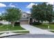 Charming two-story home with a manicured front yard, mature trees, and a two-car garage, offering classic curb appeal at 23520 San Sebastian Ct, Sorrento, FL 32776