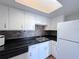 Efficient kitchen features white cabinets, black countertops, and modern backsplash at 2426 Branch Way # 200, Maitland, FL 32751
