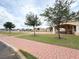 Clubhouse exterior with covered patio, red brick walkway, lawn, and mature trees creating a welcoming atmosphere at 2612 Shantiniketan Blvd # G12, Tavares, FL 32778