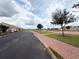 A wide street view with a red brick walkway, mature trees, and manicured lawns showcasing a peaceful community at 2612 Shantiniketan Blvd # G12, Tavares, FL 32778