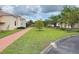 A neatly manicured lawn with a red brick walking path and shade trees between rows of cream-colored villas at 2612 Shantiniketan Blvd # G12, Tavares, FL 32778
