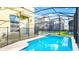 Outdoor pool area with a blue safety fence and a screened enclosure at 2791 Punctuation Pl, Kissimmee, FL 34746