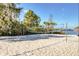 A white sand volleyball court near the lake, with blue net, and a tiki umbrella in the background at 304 Rum Run # 304, Davenport, FL 33897