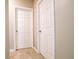 Neutral hallway displaying tile floors, baseboards, and a series of white paneled doors at 30498 Pintail Dr, Leesburg, FL 34748