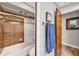 Bathroom featuring a shower and tub combo with glass doors, paired with neutral tiles, and a dark wooden door at 311 Needles Trl, Longwood, FL 32779