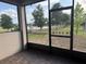 Relaxing patio view of the pond, grassy backyard, and trees, visible through the screened door at 3397 Sagebrush St, Harmony, FL 34773